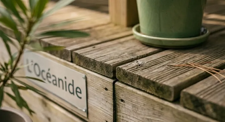 Détail d'une terrasse en bois naturel d'un hébergement de plein air avec le panneau "L'Océanide", illustrant un camping calme et sans animations en Vendée.