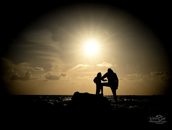 Pere et fils regardant au loin lors d'un couché de soleil