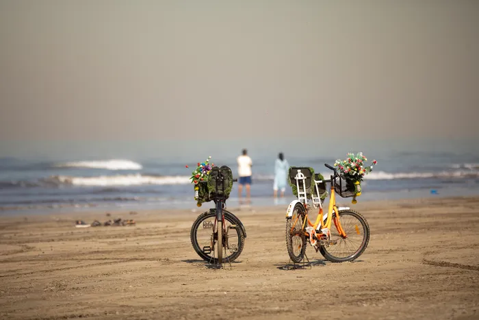 Un couple au bord de la mer laissant leur vélos derriere eux pour aller se baigner