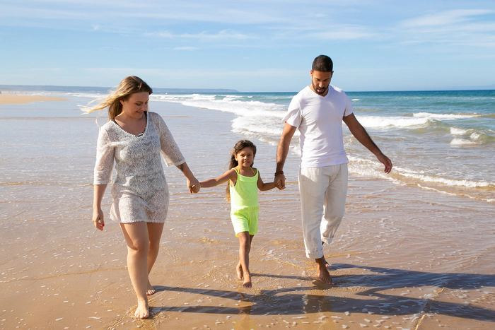 Une famille heureuse, composée de deux parents et une enfant sur la plage